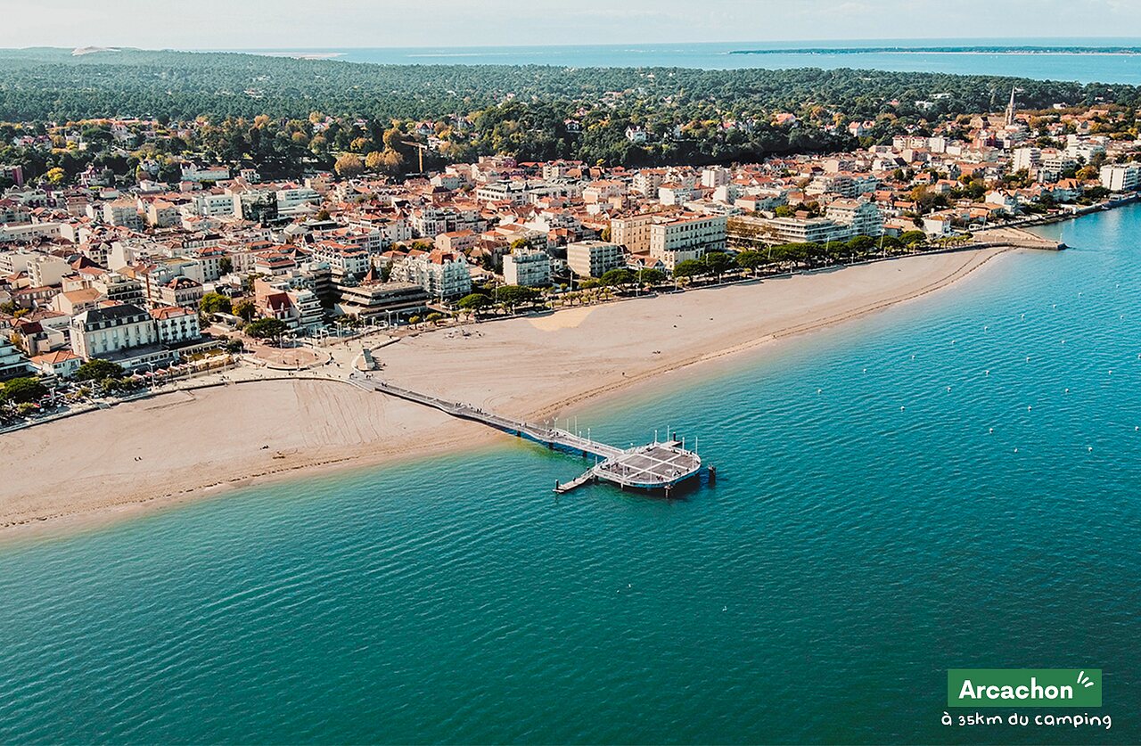 Playa de Arcachon con muelle y ciudad, lugar para visitar cerca del camping.