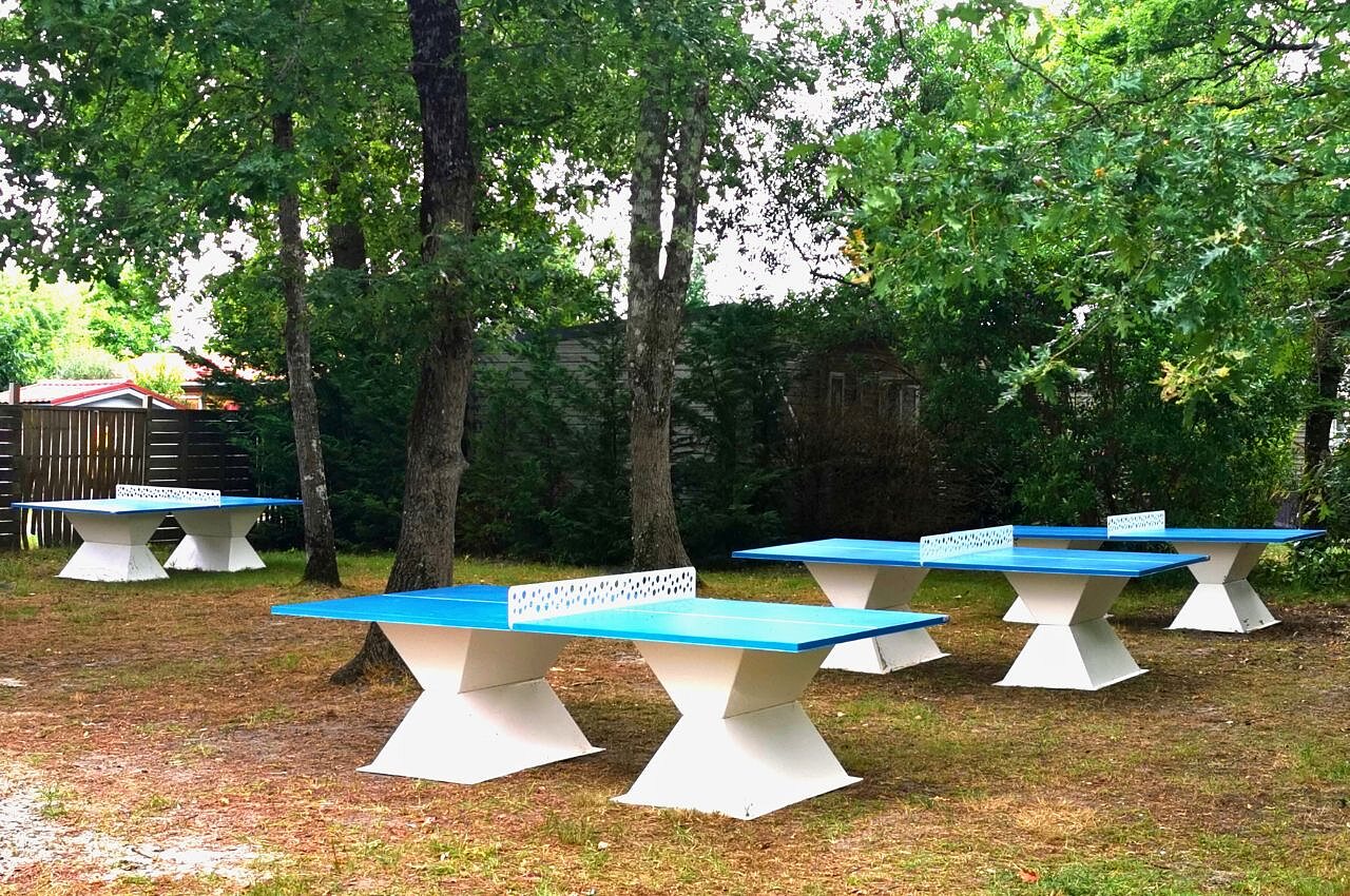 Mesas de ping-pong azules al aire libre entre �rboles en camping CLICOCHIC Bimbo en BISCARROSSE (40).