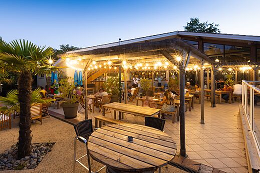 Terraza de restaurante exterior iluminada con clientes en camping CLICOCHIC Bimbo BISCARROSSE (40).