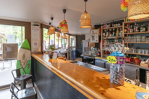 Bar interior con barra de madera y bebidas en el camping CLICOCHIC Bimbo en BISCARROSSE.