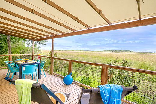 Terraza cubierta de alojamiento con mesa de comedor y vista a la naturaleza en el camping VAGUES OCEANES Blancs Chênes en LA TRANCHE SUR MER (85).