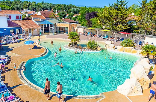 Gran piscina exterior con playa sumergida y sillas en el camping VAGUES OCEANES Bois Joly en Saint-Jean-de-Monts (85).