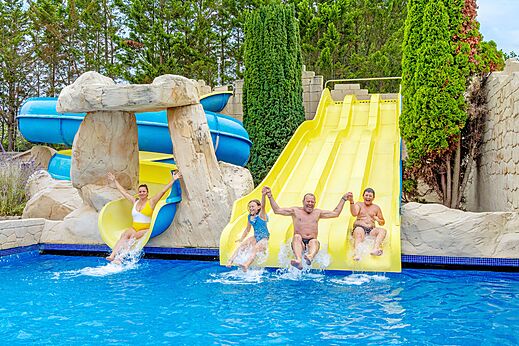 Familia en toboganes acuáticos y piscina exterior en el camping VAGUES OCEANES Bois Joly en Saint-Jean-de-Monts.
