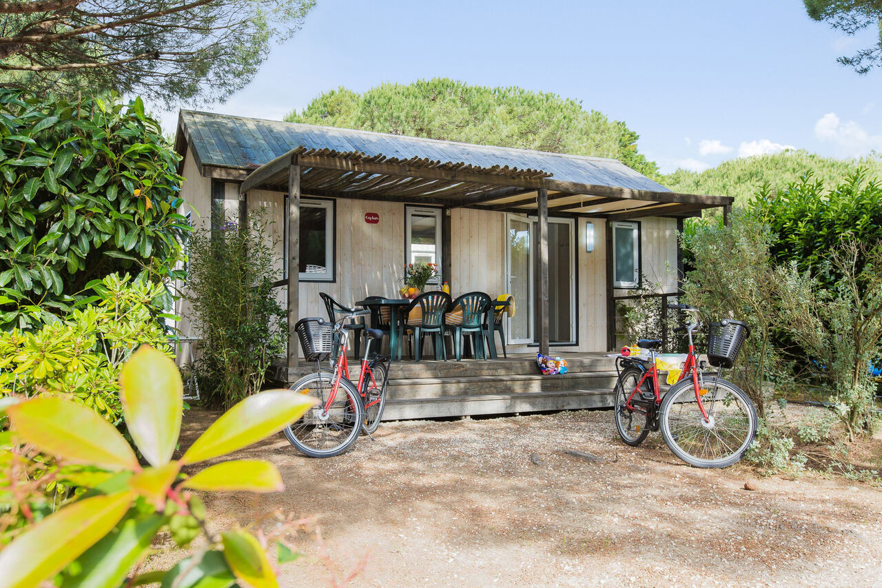 Mobil-home con terraza, mesa, sillas y bicicletas en el camping CAPFUN Bonne Etoile en BOIS PLAGE EN RE (17).