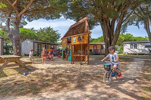Zona de juegos con estructura de madera y ni�os en bicicleta en el camping CAPFUN Bonne Etoile en BOIS PLAGE EN RE (17).