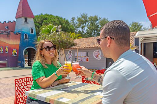 Pareja brindando con cócteles en el bar del camping CAPFUN Bonne Etoile en BOIS PLAGE EN RE (17).