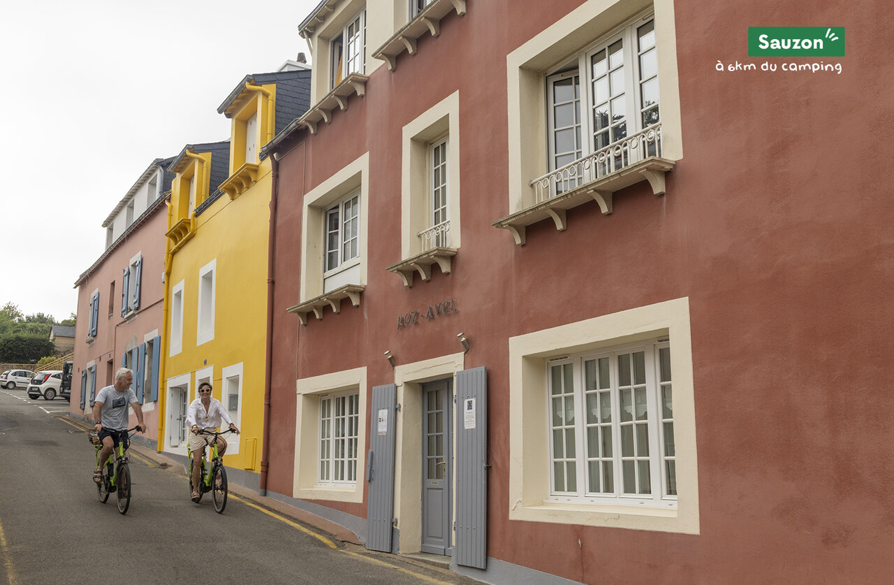 Calle colorida y ciclistas en Sauzon, ciudad para visitar cerca del camping.