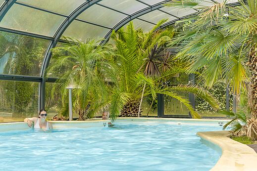 Piscina cubierta tropical con palmeras y ba�istas en el camping CLICOCHIC Bord�n�o Belle-�le-en-Mer en Le Palais (56).