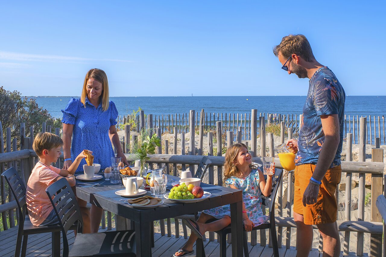 Familia desayunando en terraza con vistas al mar, camping CAPFUN Boucanet, LE GRAU DU ROI (30).