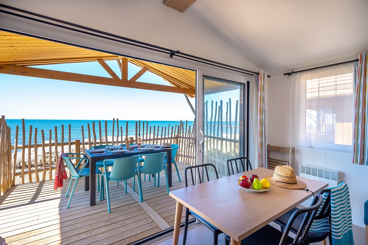 Terraza de alojamiento con mesa, sillas y vista al mar en la playa del camping CAPFUN Boucanet en LE GRAU DU ROI (30).