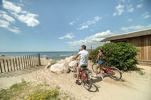 Pareja en bicicleta en la playa en el camping CAPFUN Boucanet en LE GRAU DU ROI (30).