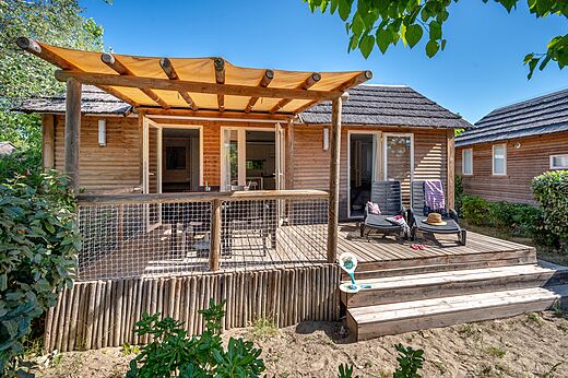 Mobil-home de madera con terraza y sillas en camping CAPFUN Boucanet.