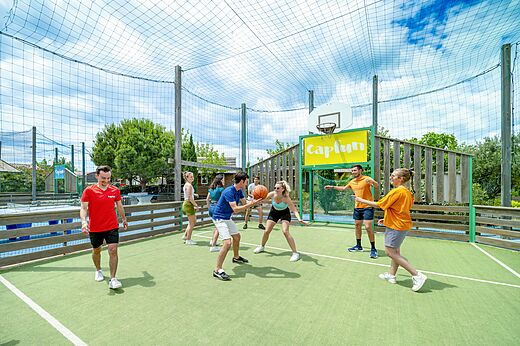 Cancha multideporte y jóvenes jugando baloncesto en camping CAPFUN Boucanet.