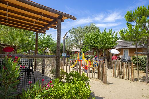 Parque infantil colorido y Mobil-homes de madera en el camping CAPFUN Boucanet en LE GRAU DU ROI (30).