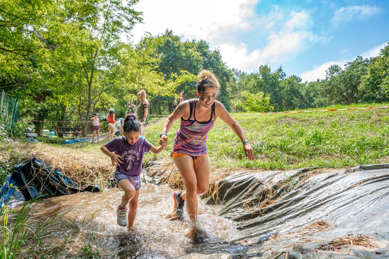 Madre e hija sonriendo en carrera de obst�culos con barro en camping VAGUES OCEANES Boudigau en LABENNE OCEAN (40).