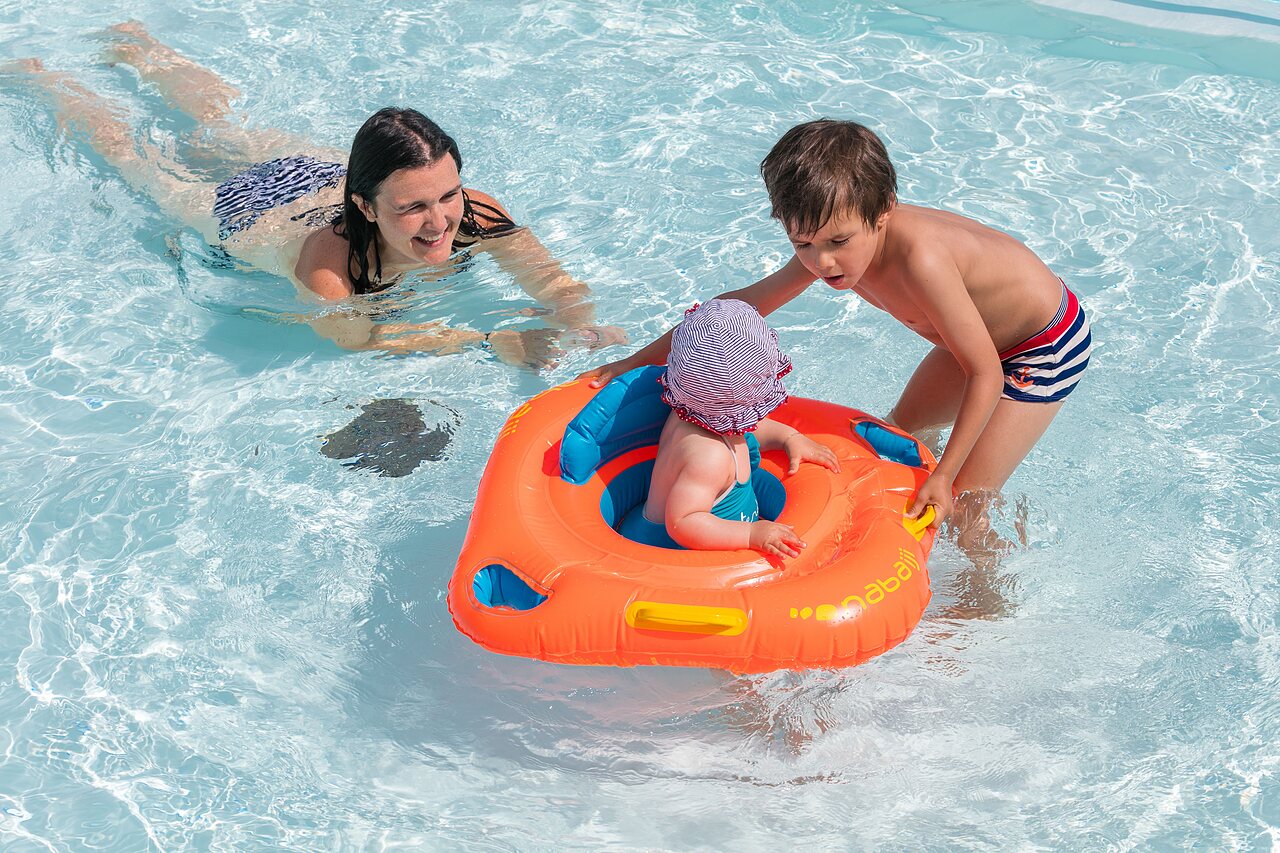 Familia con beb� en flotador, piscina exterior en el camping CLICOCHIC Brandais.