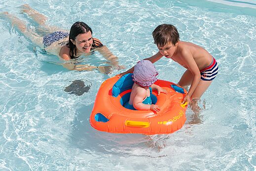Piscina familiar con bebé en flotador en el camping CLICOCHIC Brandais en Brem sur Mer.