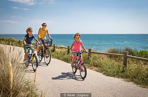 Familia en bicicleta junto al mar en el camping CLICOCHIC Brandais.