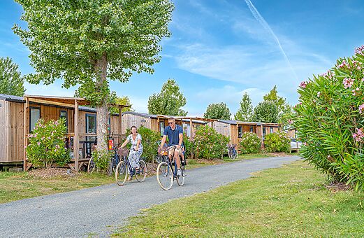 Paseo en bicicleta frente a casas móviles de madera en el camping CLICOCHIC Brandais.