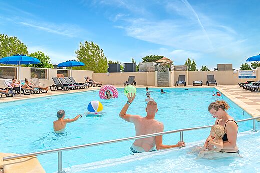 Piscina exterior con familias y niños, sillas, en el camping CLICOCHIC Brandais en Brem sur Mer (85).