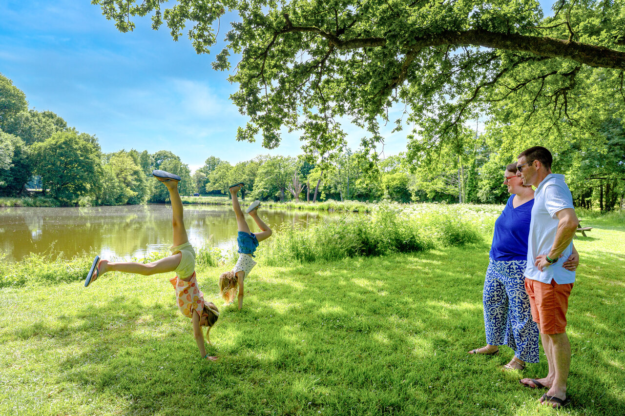Ni�os haciendo volteretas cerca del lago, en el camping CAPFUN Breteche en Les Epesses (85).