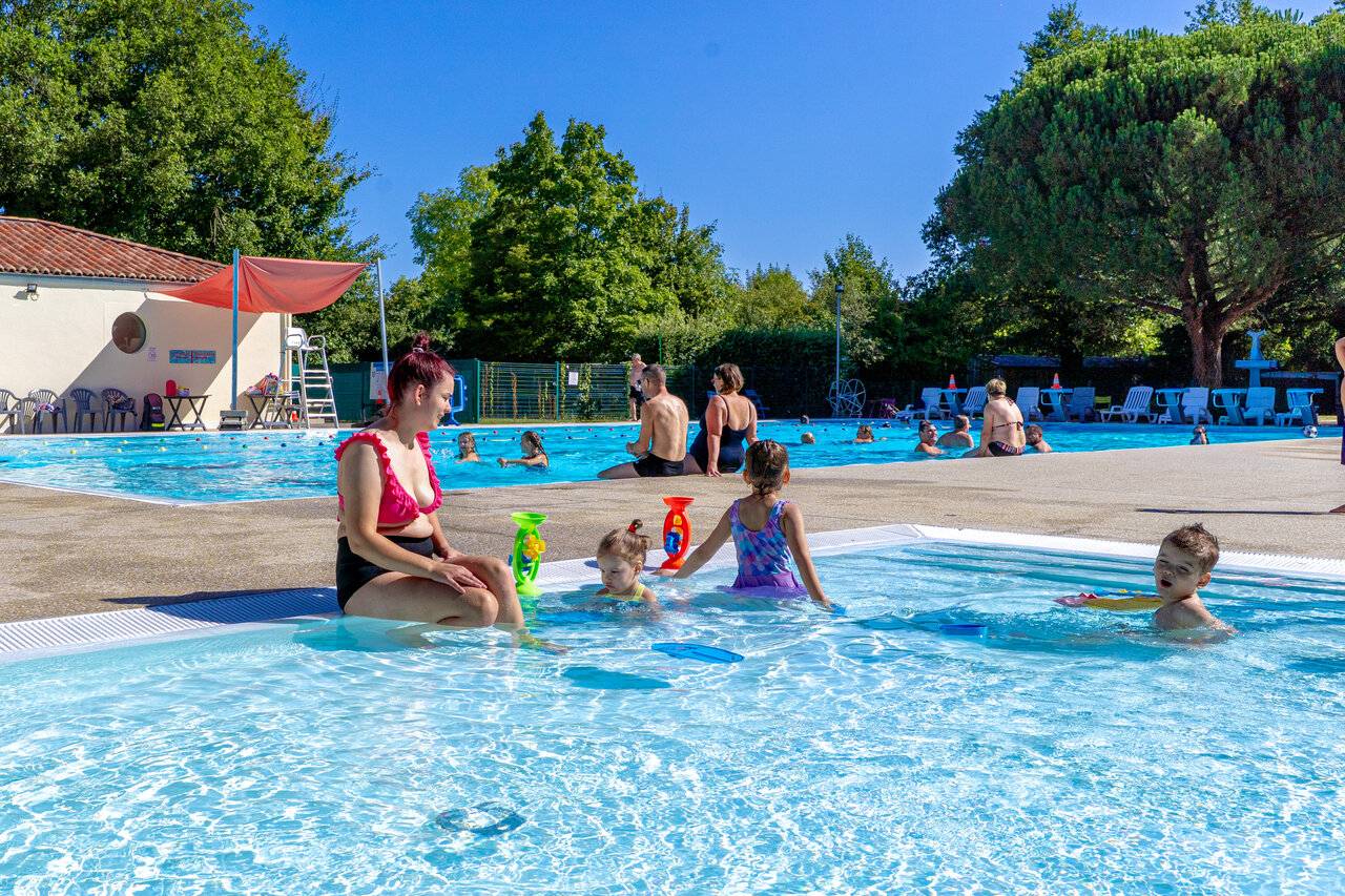 Familia y ni�os en la piscina exterior del camping CAPFUN Breteche en Les Epesses.