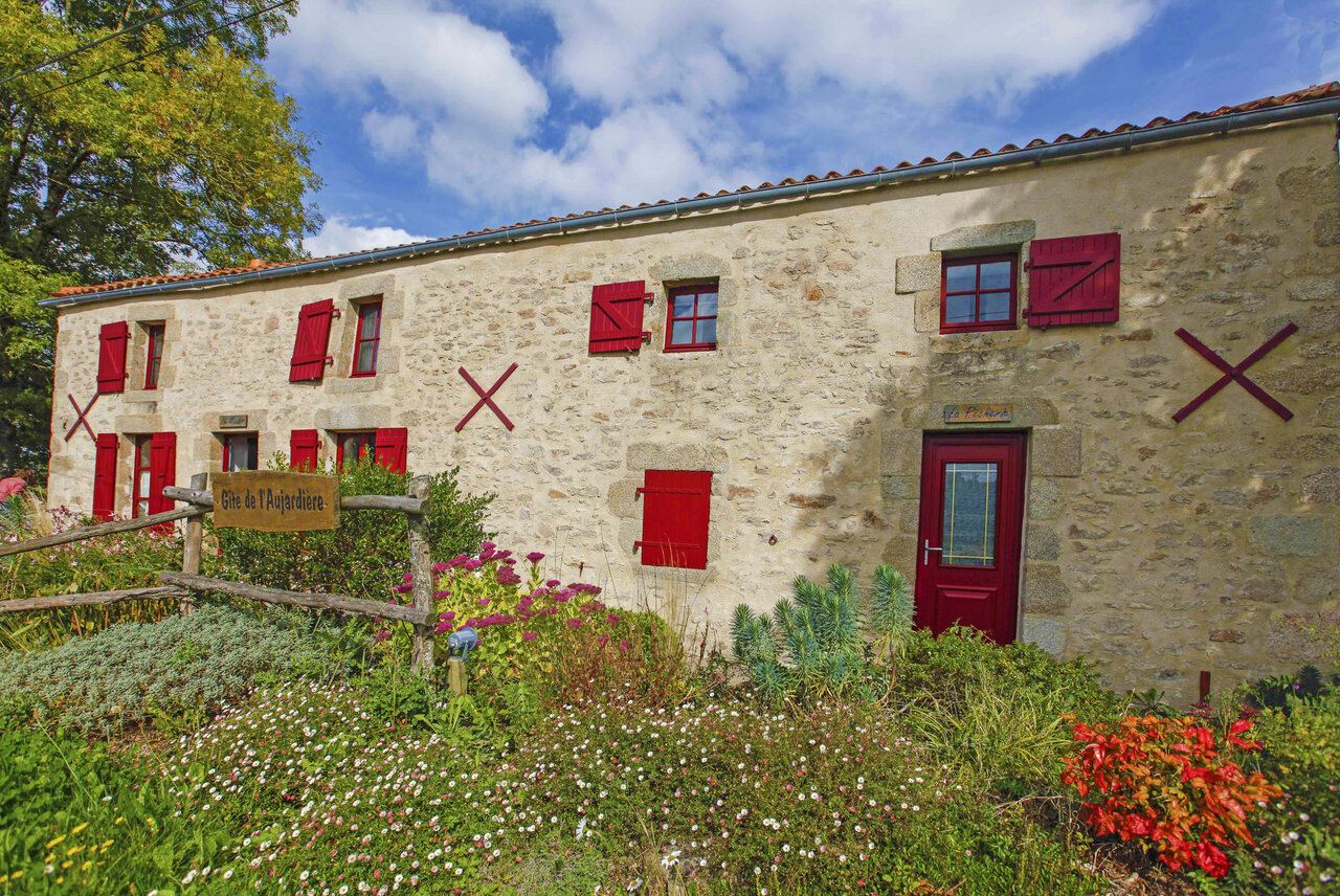 Casa rural de piedra, contraventanas rojas, jard�n florido en CAPFUN Breteche, Les Epesses.