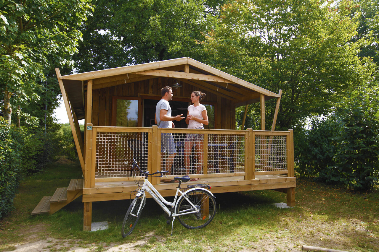 Chalet de madera, pareja en terraza, bicicleta en CAPFUN Breteche Les Epesses (85).