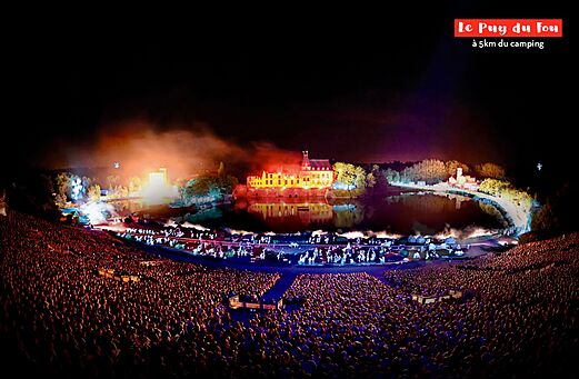 Espectáculo nocturno grandioso en Puy du Fou, castillo iluminado y efectos especiales.