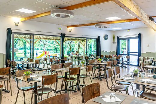 Restaurante del camping con muchas mesas en CAPFUN Breteche en Les Epesses (85).