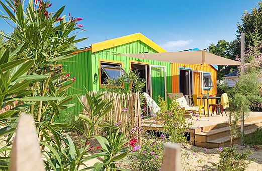 Mobil-home colorido con terraza de madera y muebles exteriores en el camping CLICOCHIC Cabanes d Oléron en ST GEORGES D'OLERON (17)