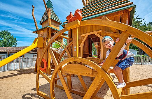 Parque infantil de madera con tobogán y niño en el camping CLICOCHIC Cabanes d Oléron en ST GEORGES D'OLERON (17).