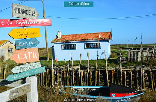 Señalización colorida y casa típica junto al agua en Château d'Oléron.