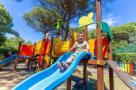 Niño sonriendo en un tobogán colorido del parque infantil en el camping CAPFUN Campo dei Fiori en Rosignano Marittimo (57).