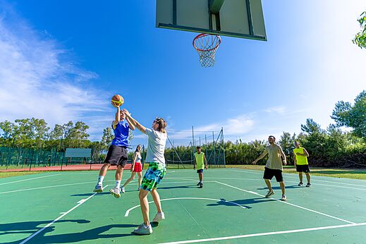 Cancha multideporte con jóvenes jugando baloncesto en el camping CAPFUN Campo dei Fiori en Rosignano Marittimo (57).