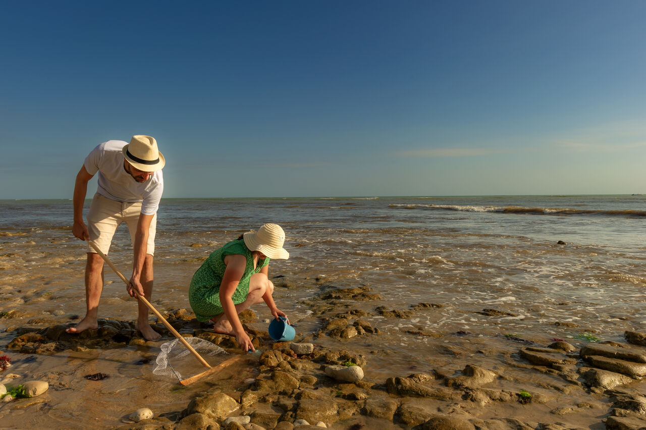 Pareja pescando a pie en una playa rocosa en el camping CLICOCHIC Camp du Soleil en Ars-en-R� (17).