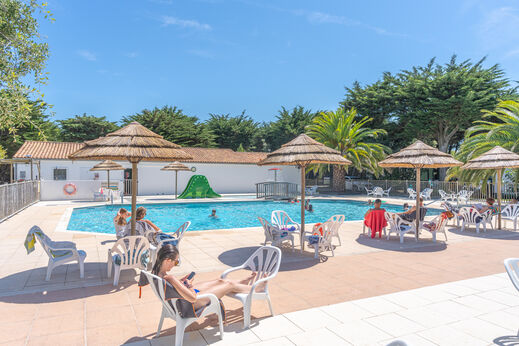 Piscina exterior, tobogán y sillas en el camping CLICOCHIC Camp du Soleil.
