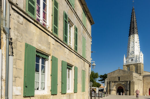Iglesia histórica con campanario puntiagudo y casas tradicionales en Ars-en-Ré.