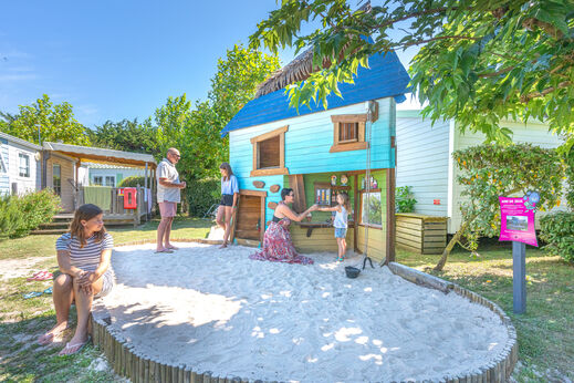 Zona de juegos con casita y arenero para niños en el camping CLICOCHIC Camp du Soleil en Ars-en-Ré (17).
