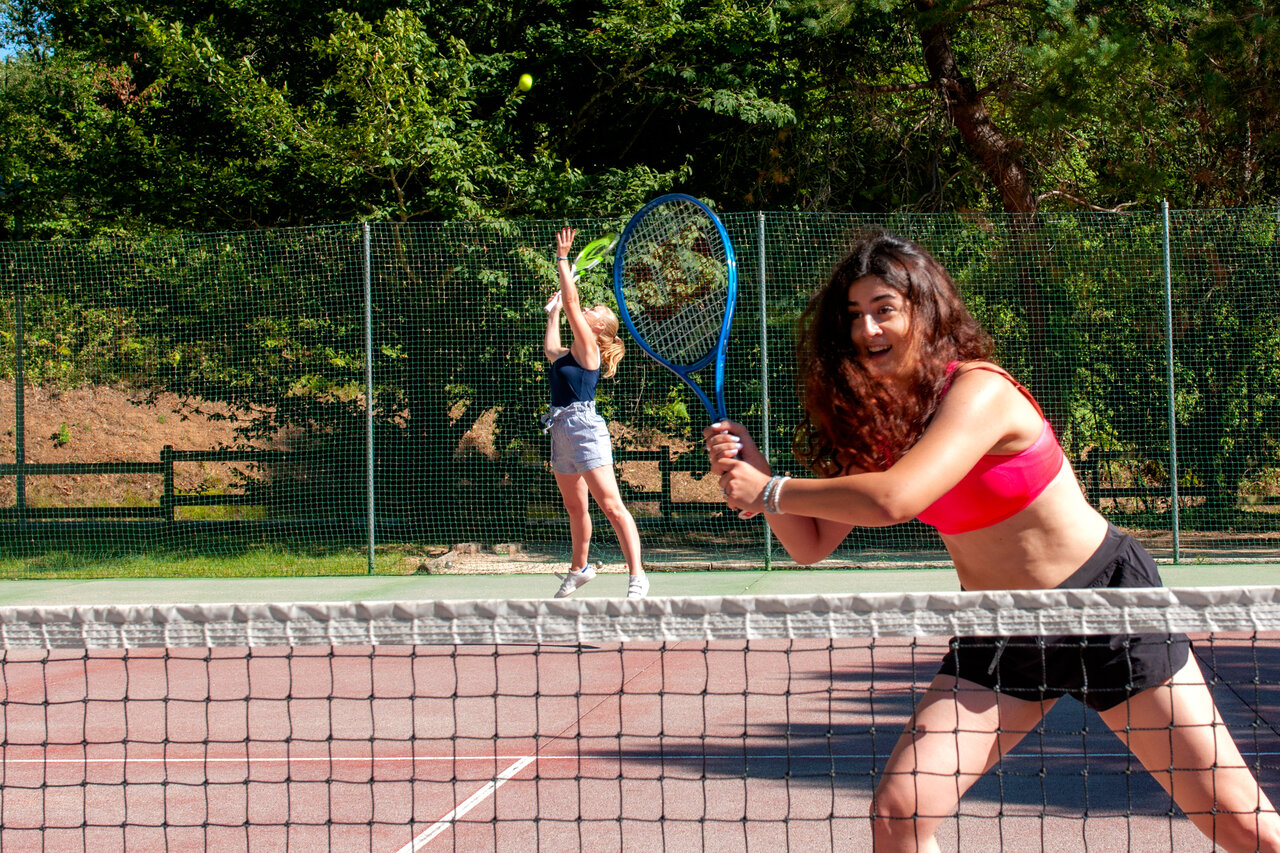 J�venes jugando tenis en la cancha del camping CAPFUN El Canto La Gallina.