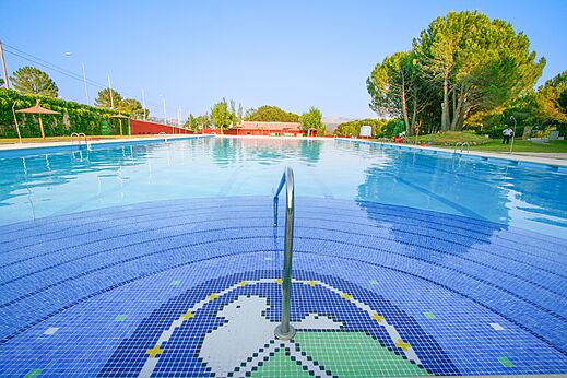 Piscina exterior con mosaicos y pasamanos en el camping CAPFUN El Canto La Gallina (Madrid).