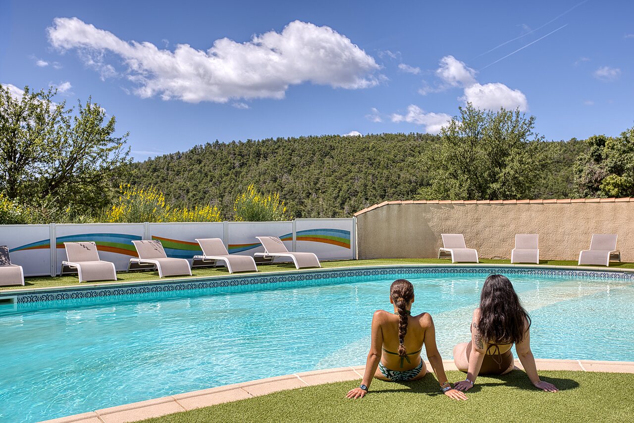 Piscina exterior, tumbonas y dos mujeres en el camping CLICOCHIC Castillon de Provence.