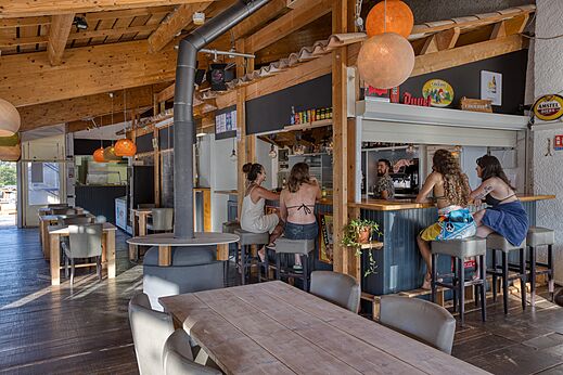 Bar y restaurante de madera con clientes en el camping CLICOCHIC Castillon de Provence en Castellane (04).