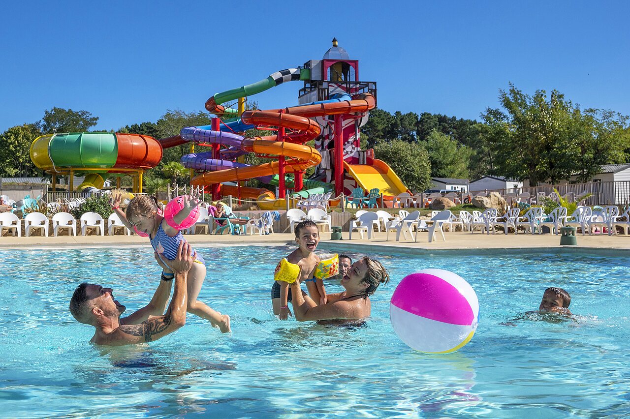 Piscina exterior con toboganes y familia en el camping CAPFUN Cenic en PENESTIN (56).