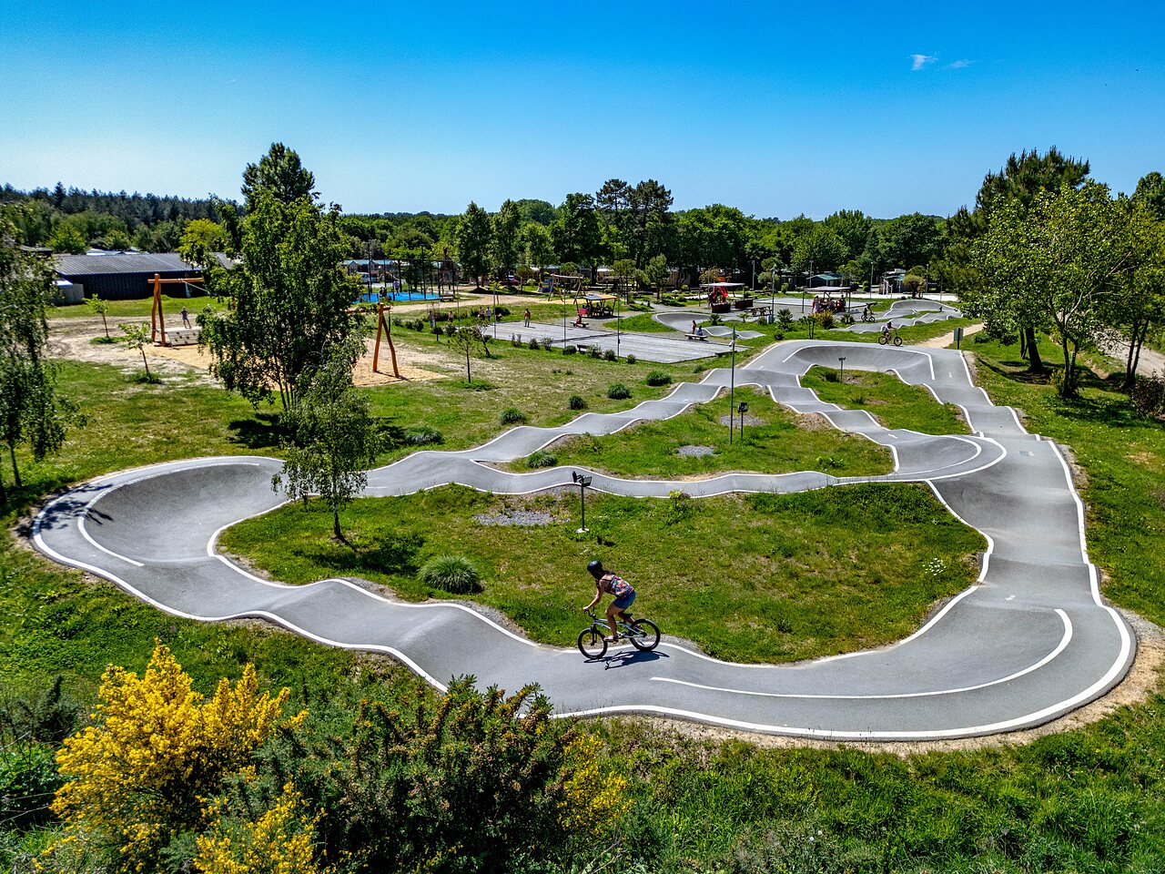 Pista pump track moderna con ciclista, zona de juegos en camping CAPFUN Cenic en PENESTIN (56).
