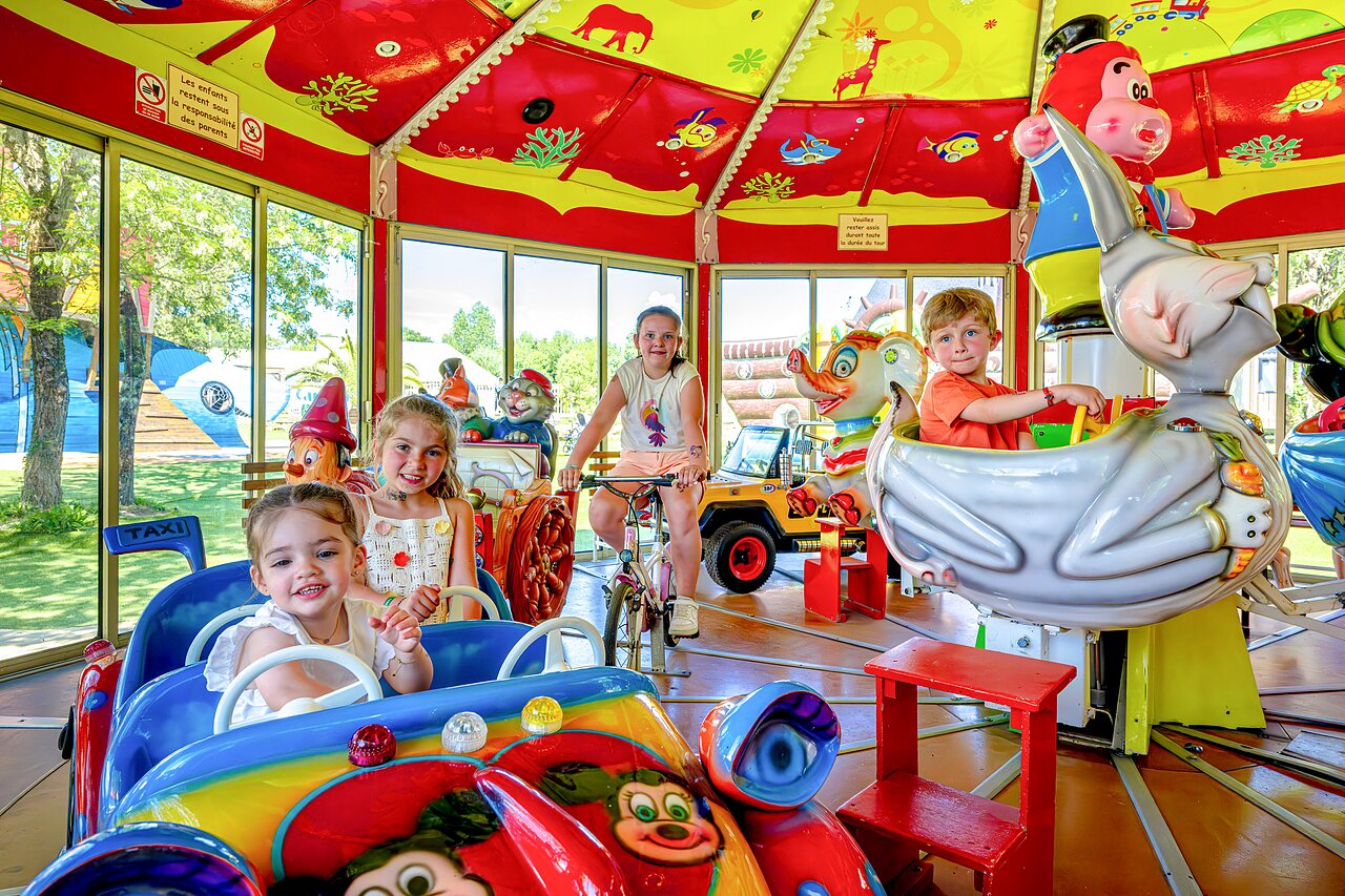 Ni�os en carrusel, �rea de juegos interior en camping CAPFUN Cenic PENESTIN (56).
