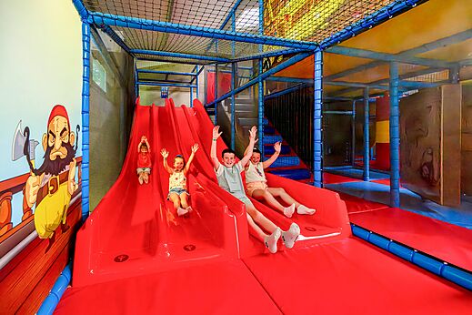 Zona de juegos interior con toboganes y niños en el camping CAPFUN Cenic en PENESTIN (56).