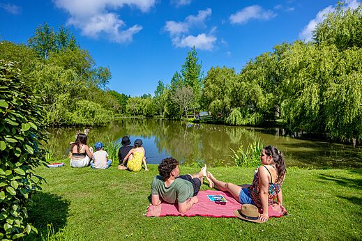 Familia relajándose junto a un estanque verde en el camping CAPFUN Cenic en PENESTIN (56).