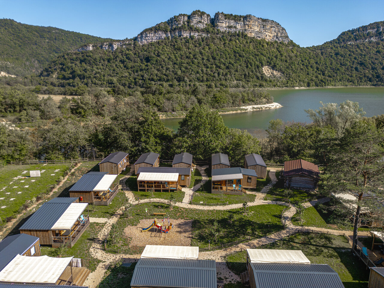 Vista a�rea alojamientos, lago y parque infantil en el camping CLICOCHIC Chancia en Chancia (01).