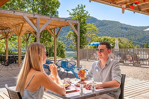 Pareja almorzando en terraza del restaurante con vista lago en camping CLICOCHIC Chancia (01).